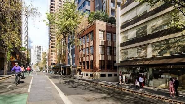 Sydney street view of a brick mixed-use building, with cyclists and pedestrians passing.